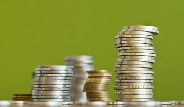 Stacks of variously sized coins are arranged against a green background.