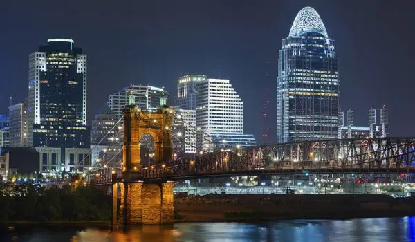 A nighttime cityscape showcases illuminated buildings and a bridge over a river, highlighting an urban skyline.