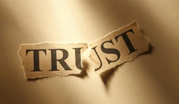 A piece of paper with the word "TRUST" torn into two parts.