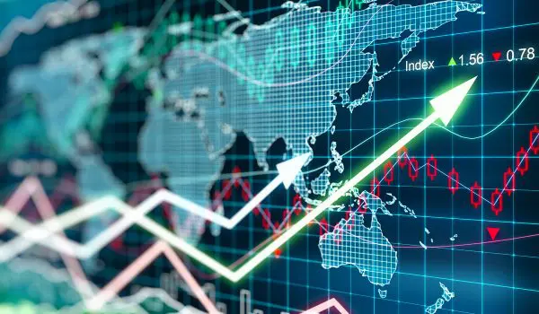 A screen displays a rising stock market graph with various global indexes, highlighting financial growth against a world map backdrop.