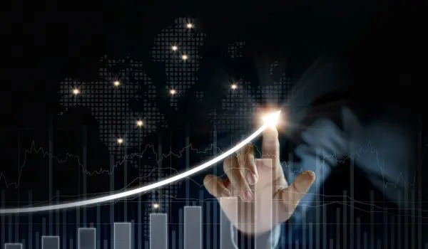 A hand is interacting with a digital graph that overlays a map, symbolizing financial or data trends on a global scale.