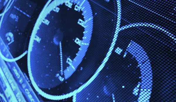 A close-up view of a digital car dashboard with glowing blue speedometers and dials.