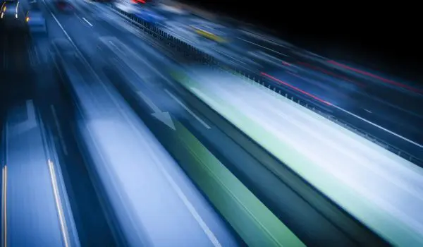 Vehicles captured in motion at night, creating streaks of light due to long exposure photography.