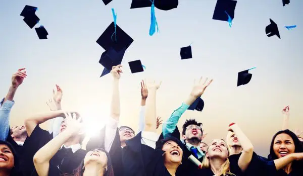 Smiling Students Throwing Graduation Caps In Air