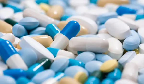 A variety of colorful pills and capsules are scattered closely together.