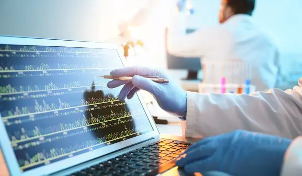 A person is analyzing a graph on a laptop screen in a laboratory environment.