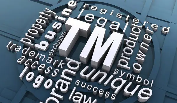 A 3D conceptual art of various words such as "legal," "trademark," "symbol," and "law" interconnected around a central "TM" logo, representing elements related to trademark law on a blue background.