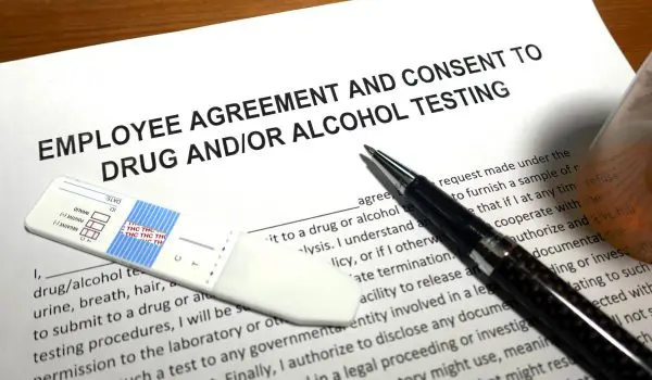 A document titled "EMPLOYEE AGREEMENT AND CONSENT TO DRUG AND/OR ALCOHOL TESTING" with a pen and a swab on top of it.