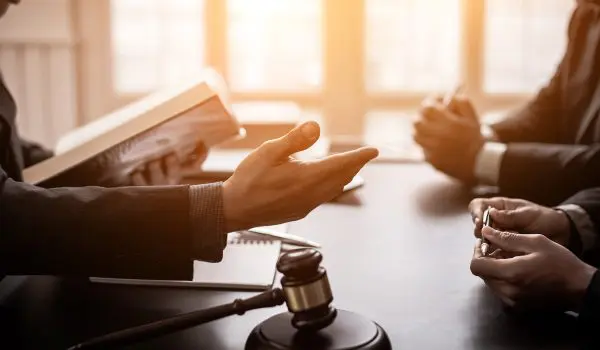 Individuals are engaged in a discussion with a gavel on the table, suggesting a legal or formal setting.