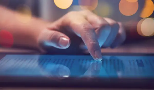 A person is using a tablet with a blurred colorful background.