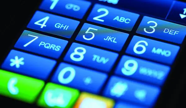 A close-up view of a cellphone keypad with illuminated blue buttons displaying numbers and corresponding letters.
