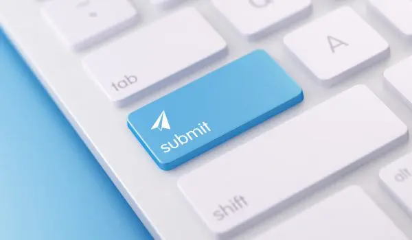 A close-up of a modern white keyboard with a blue "submit" key highlighted and an arrow cursor icon pointing upwards.