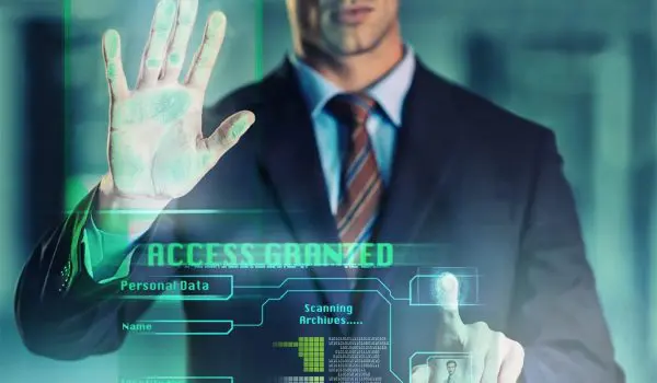 A man in a suit is interacting with a futuristic transparent touchscreen displaying "Access Granted" and other digital information.