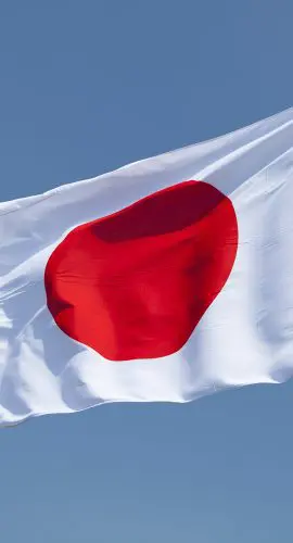 A Japanese flag flutters against a clear blue sky.