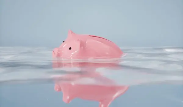 A pink piggy bank is floating on a water surface.