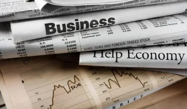Stack of newspapers with headlines related to business and the economy.