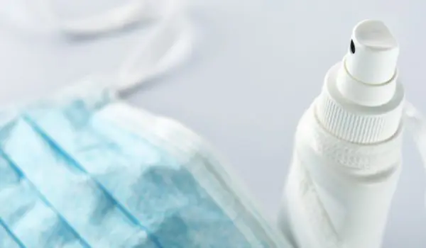 A face mask lies next to a spray bottle.
