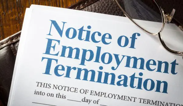 A document titled "Notice of Employment Termination" is partially covered by a pair of glasses.