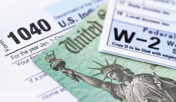 Various tax forms, including a 1040 and a W-2, are displayed alongside a depiction of the Statue of Liberty.