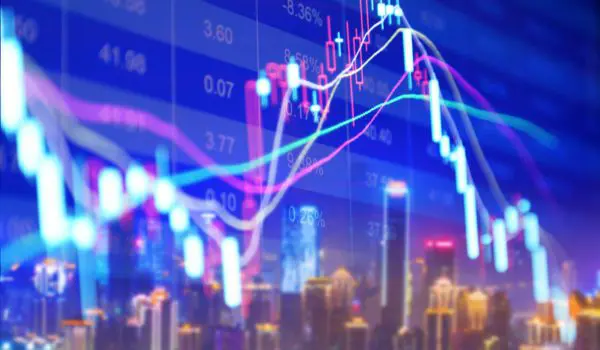 A colorful stock market chart is superimposed over a blurred cityscape at night.