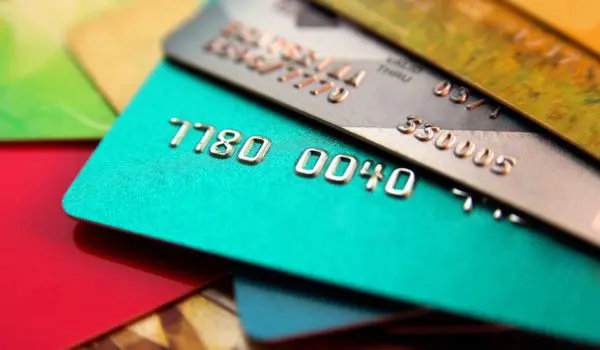 A stack of colorful credit cards is spread out, displaying some of the card numbers.