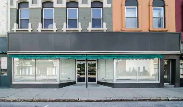 A row of storefronts with large display windows and colorful upper facades.
