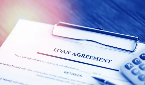 A loan agreement document on a clipboard is placed next to a calculator.