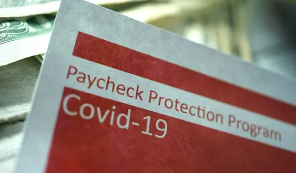 A document labeled "Paycheck Protection Program Covid-19" is partially visible with money in the background.