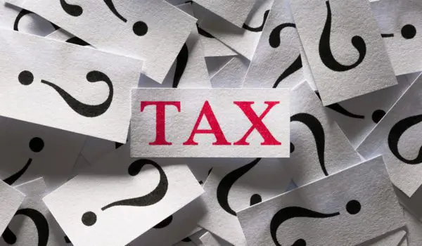 A red "TAX" is surrounded by multiple white cards with black question marks on them.