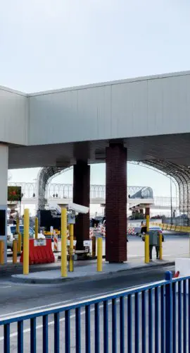 A border crossing checkpoint with multiple lanes is equipped with toll booths and barriers.