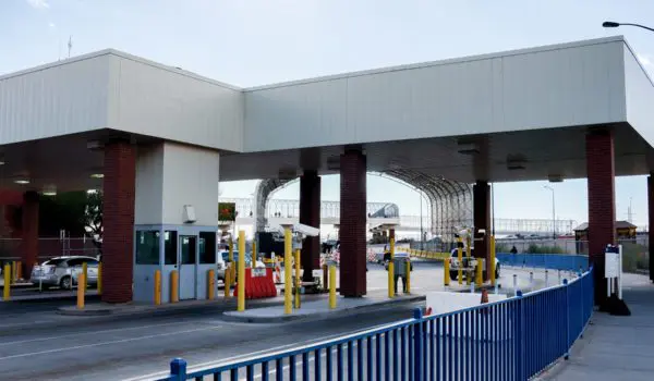 A border crossing checkpoint with multiple lanes is equipped with toll booths and barriers.