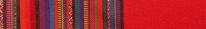 A colorful woven textile features an array of intricate patterns and stripes in red, blue, green, yellow, and purple.