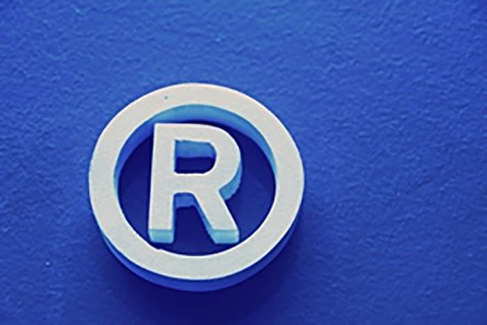 A white "R" encircled with a white border is set against a blue backdrop.