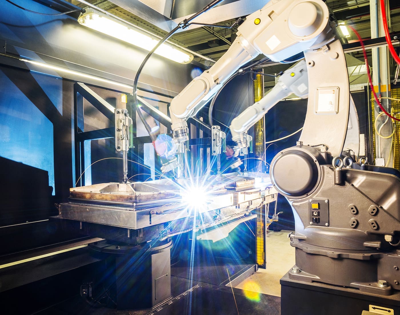 A robotic arm performs a welding operation on a metal assembly in an industrial environment.