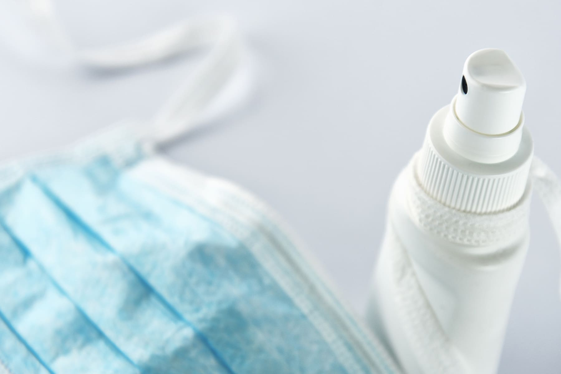 A face mask lies next to a spray bottle.