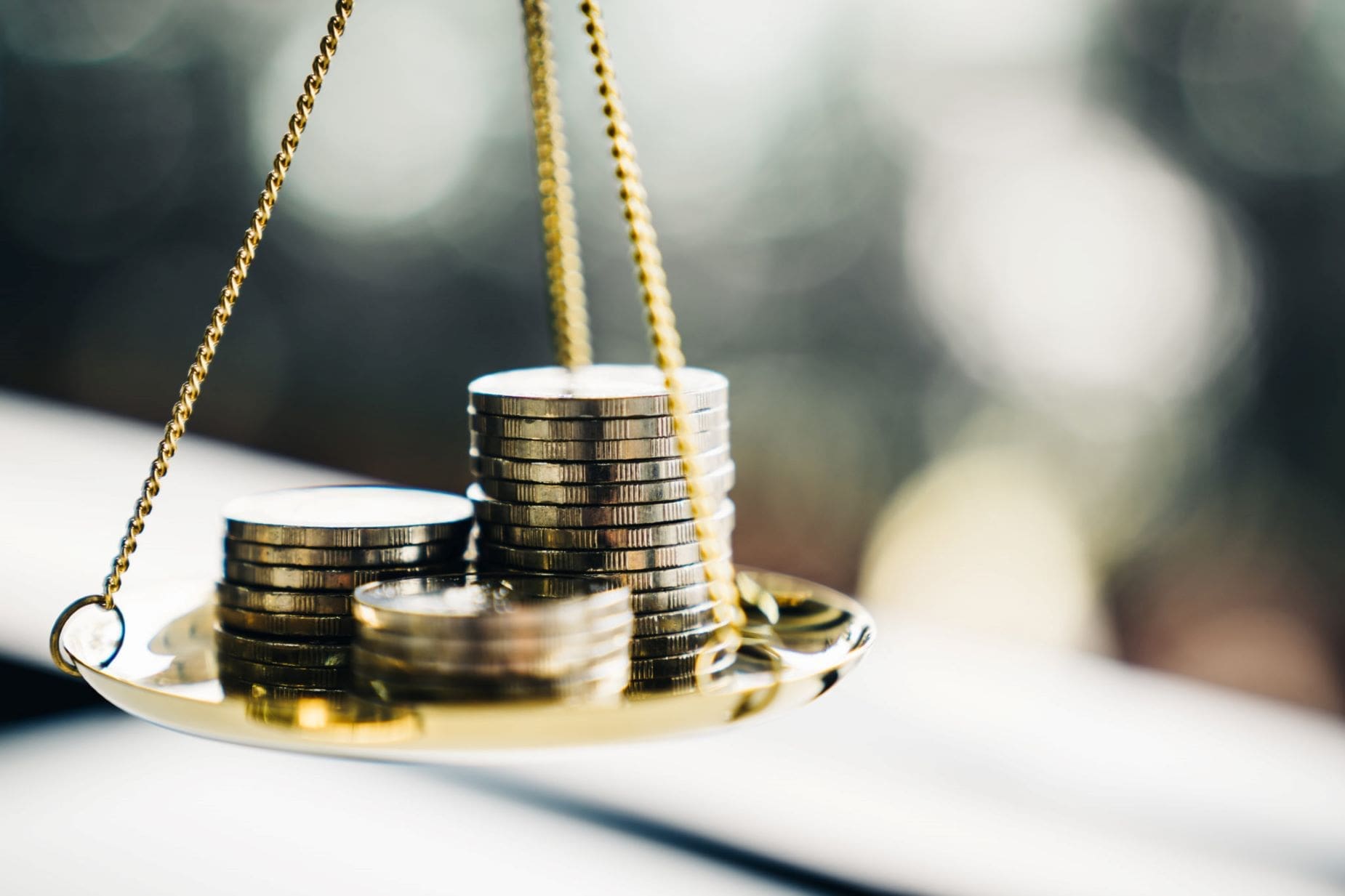 A balance scale is holding stacks of coins.