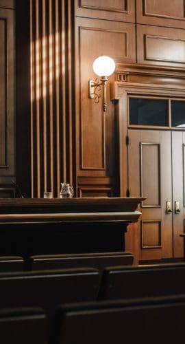 Empty American Style Courtroom. Supreme Court of Law and Justice Trial Stand. Courthouse Before Civil Case Hearing Starts. Grand Wooden Interior with Judge's Bench, Defendant's and Plaintiff's Tables.