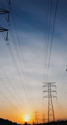 Modern power lines against bright setting sun