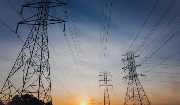 Modern power lines against bright setting sun