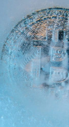 Prague, Czech Republic - October, 2019: Silver Bitcoin, bit coin online digital currency frozen in the blue ice. Concept of block chain, crypto market crash. Frozen crypto money, depreciation