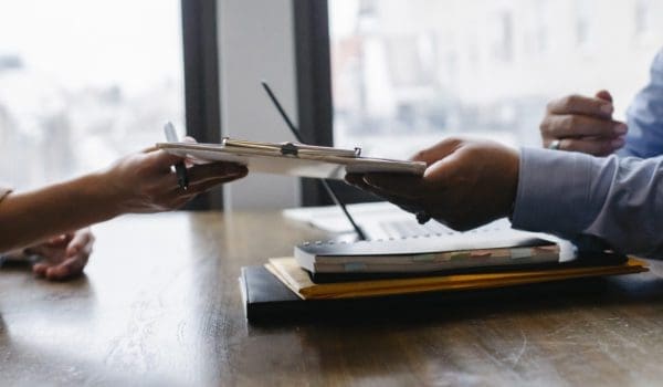 Crop black job candidate passing resume to hr employee