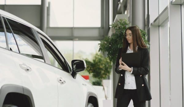 Employee of luxurious dealership standing in front of car