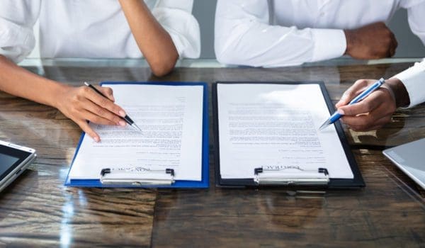 Two Businesspeople Working On Contract Paper In Office