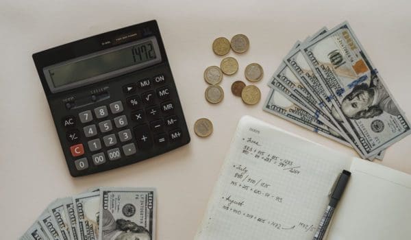 Black calculator beside coins and notebook