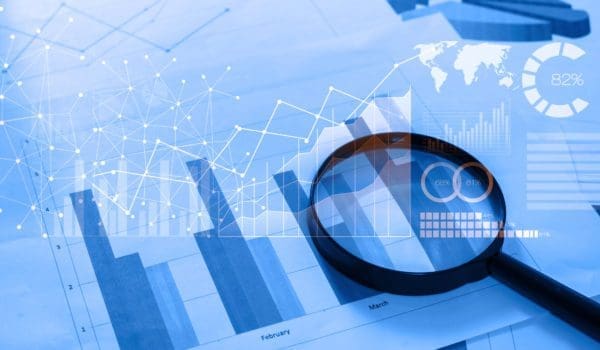Magnifying glass and documents with analytics data lying on table,selective focusMagnifying glass and documents with analytics data lying on table,selective focus