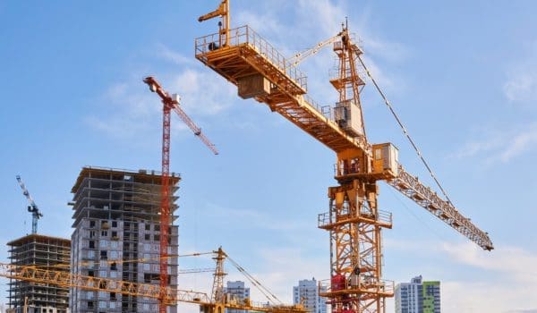 several construction tower cranes of different heights at a building site during the construction of blocks of flats, view against the sky
