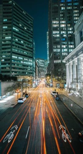 Cars on road between high rise buildings during night time
