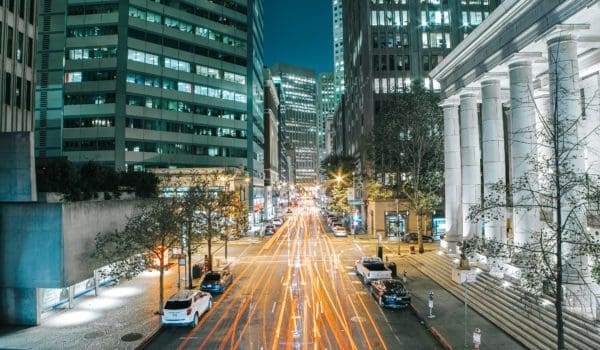 Cars on road between high rise buildings during night time