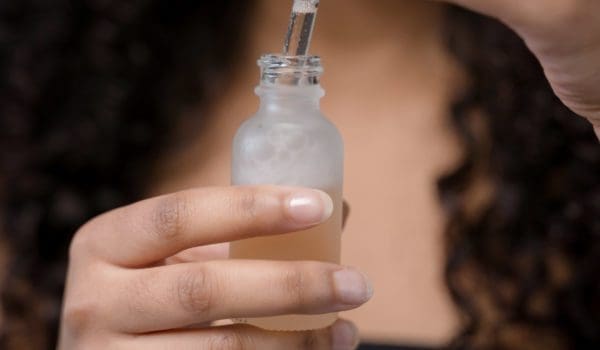 Person holding clear glass bottle