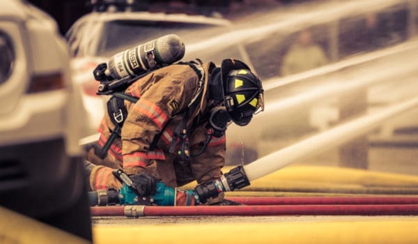 Firefighter holding hose with water flowing